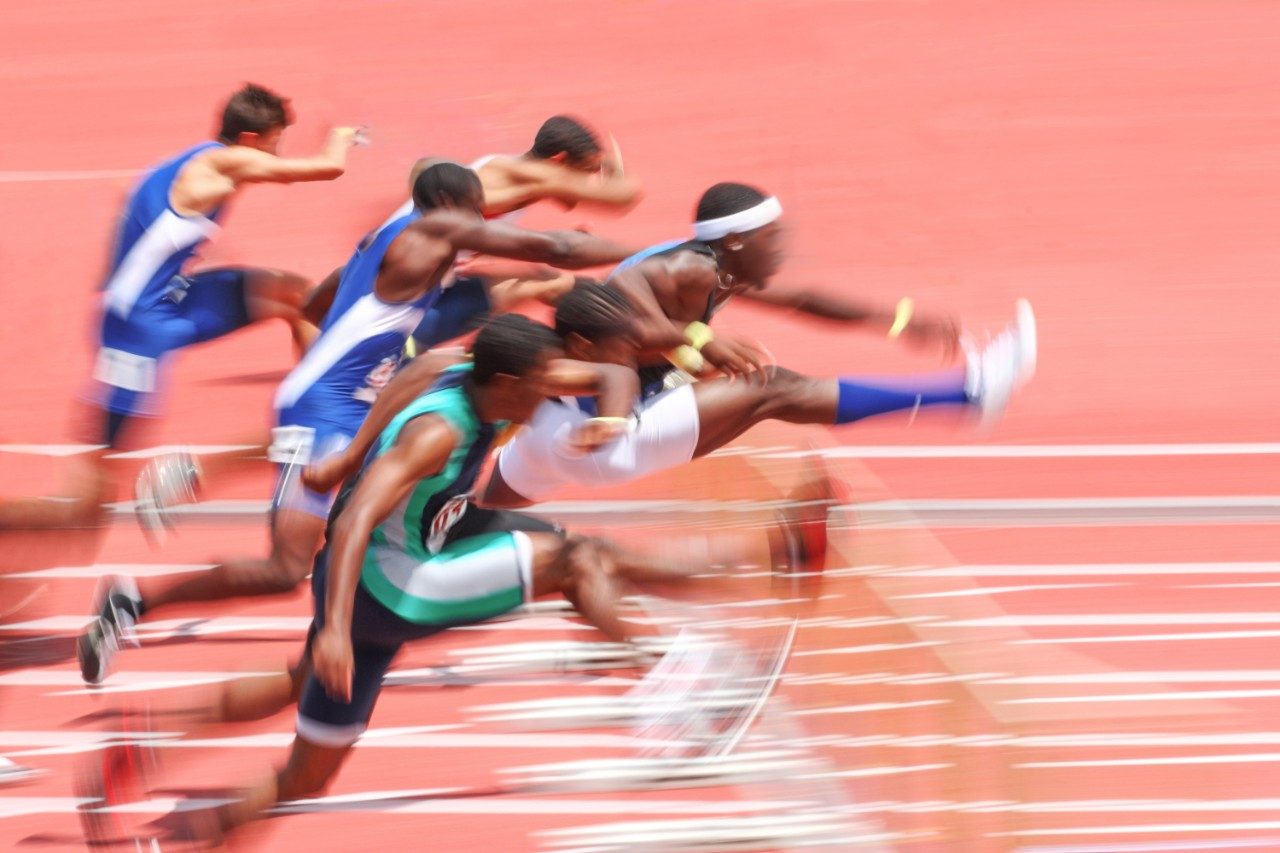 Runners jumping hurdles competing in race