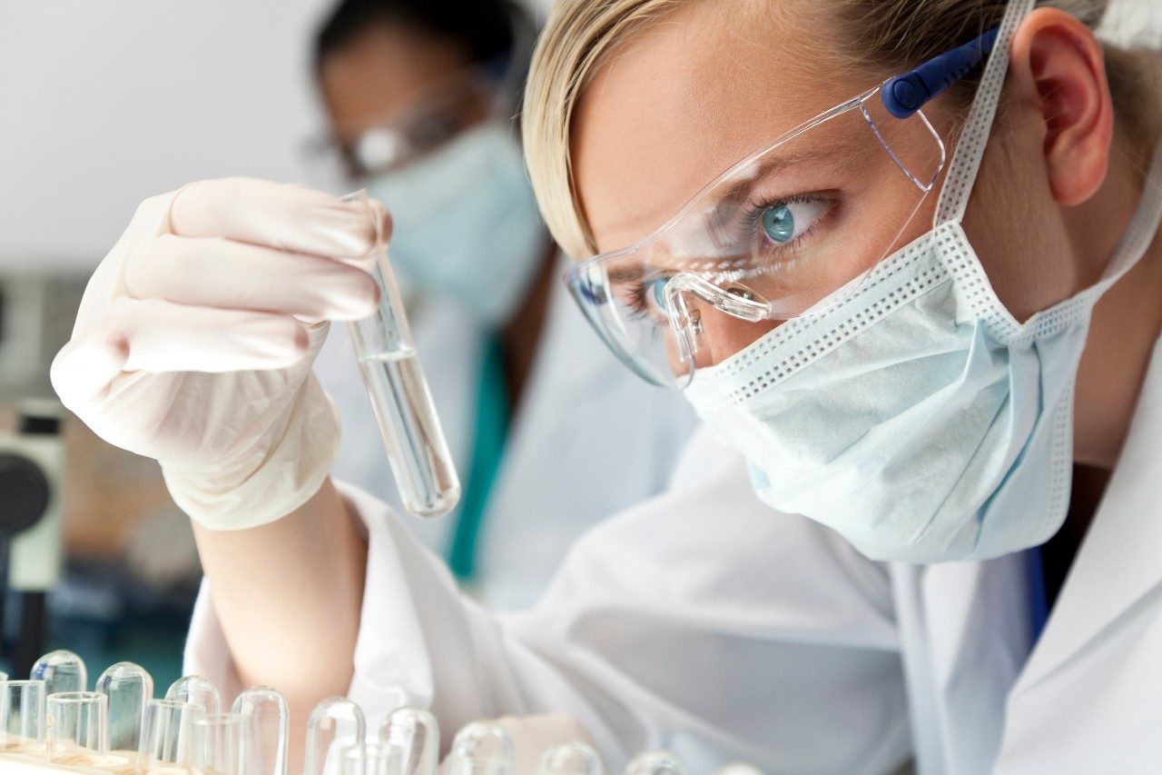 Scientific researcher in a lab looking at vial