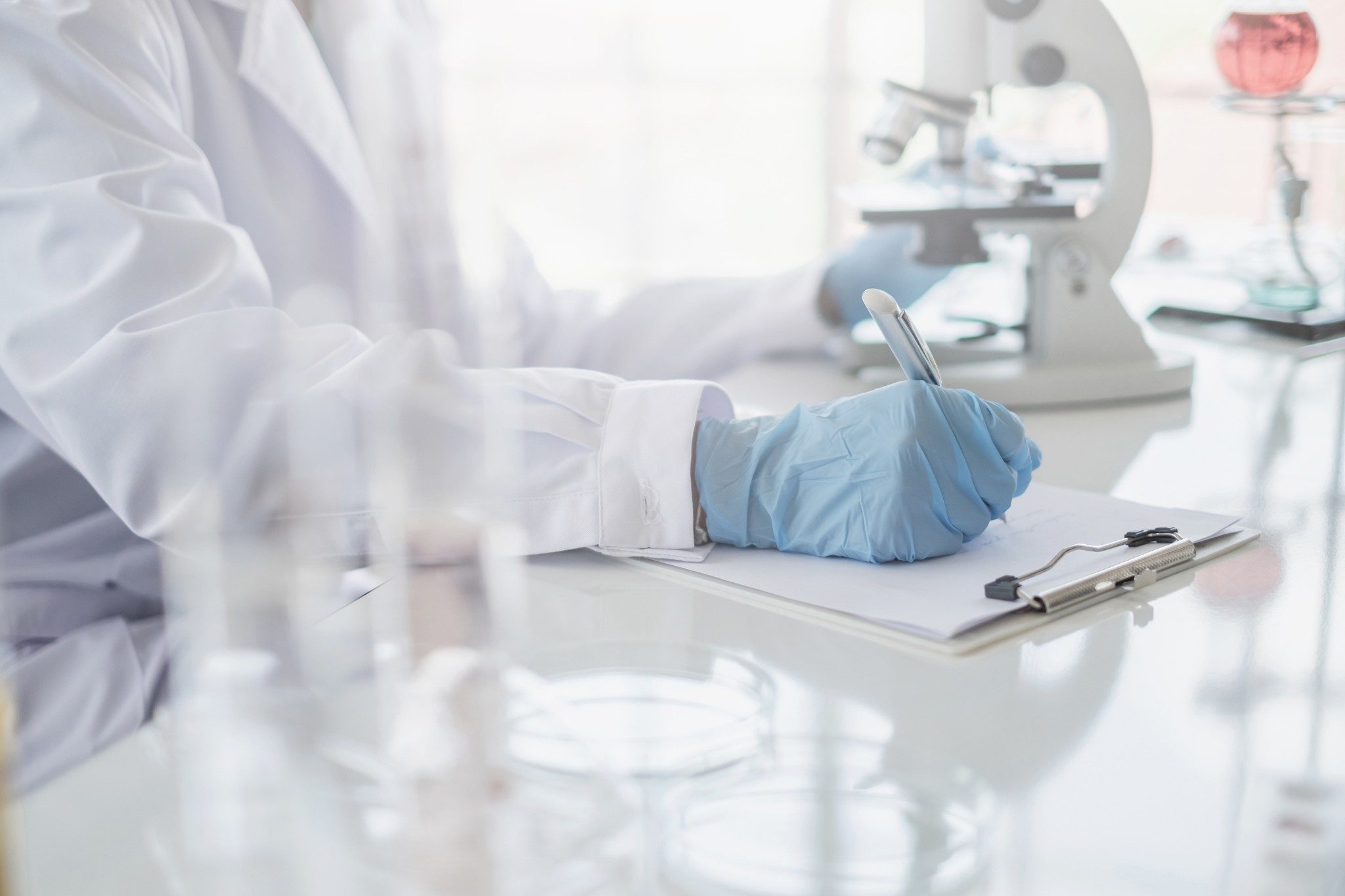 A scientist writing on a clipboard in laboratory