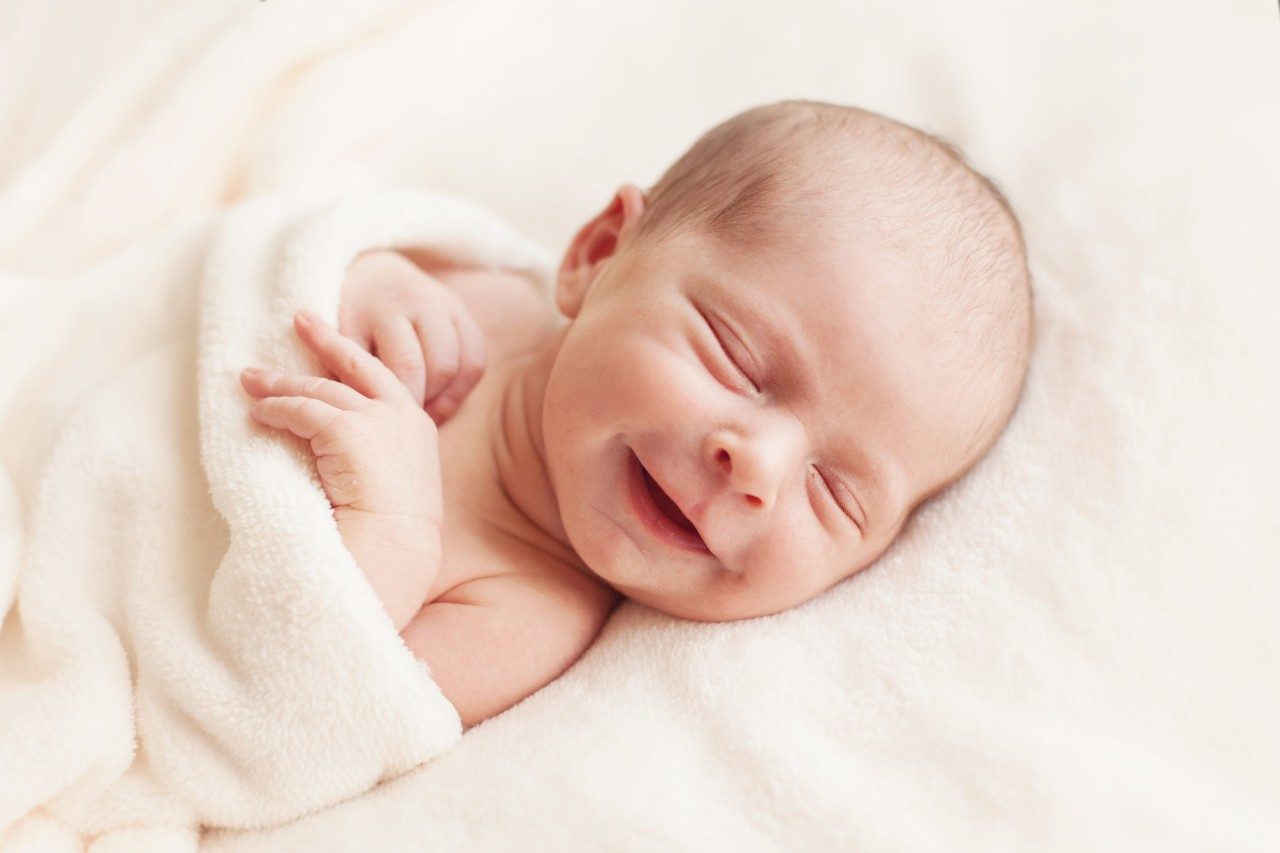 Newborn baby smiling in blanket