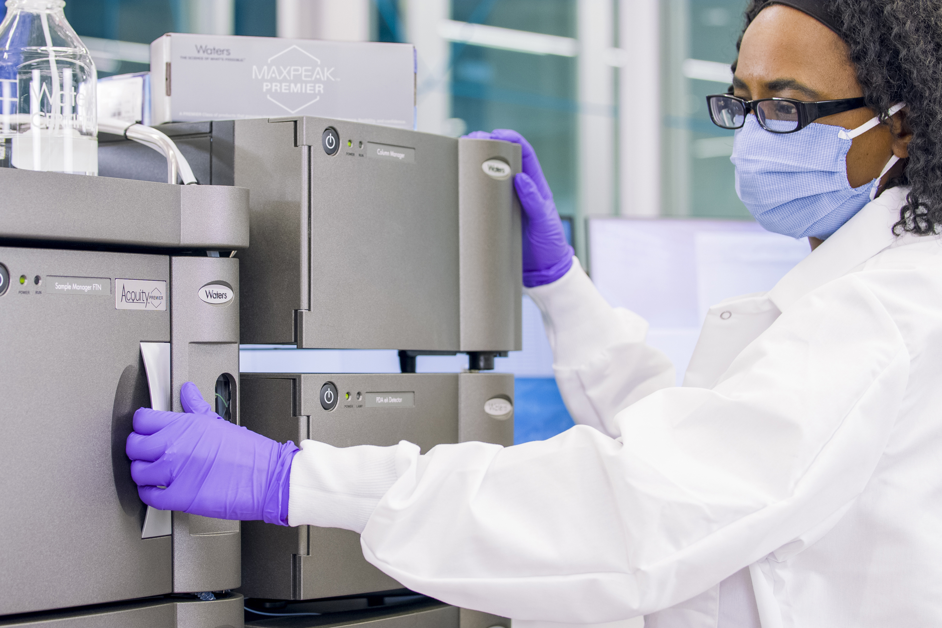 Una investigadora abriendo la puerta del sistema ACQUITY Premier en el laboratorio